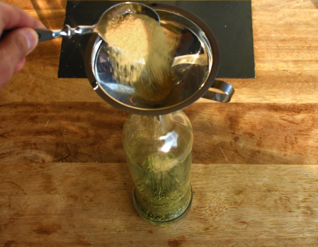 Nach dem Einfüllen der Olivenblätter in die Flasche wird der Rohrzucker dazugegeben.