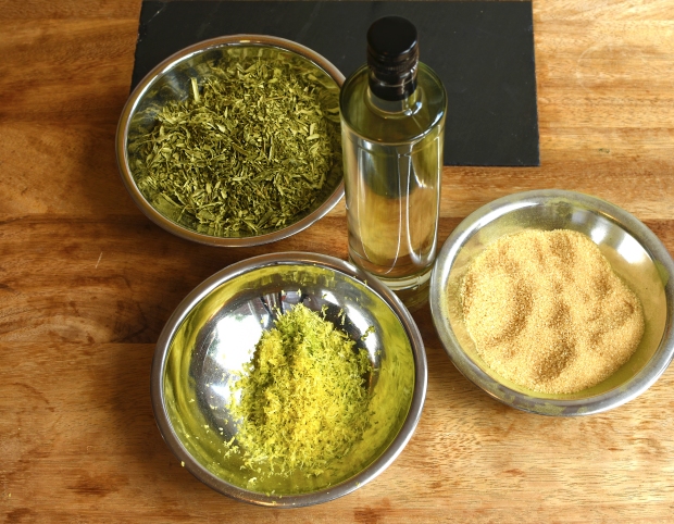Die Zutaten für einen selbstgemachten Olivenblätter-Likör sind Olivenblättertee, geriebene Zitronenschalen, Rohrzucker und Wodka.